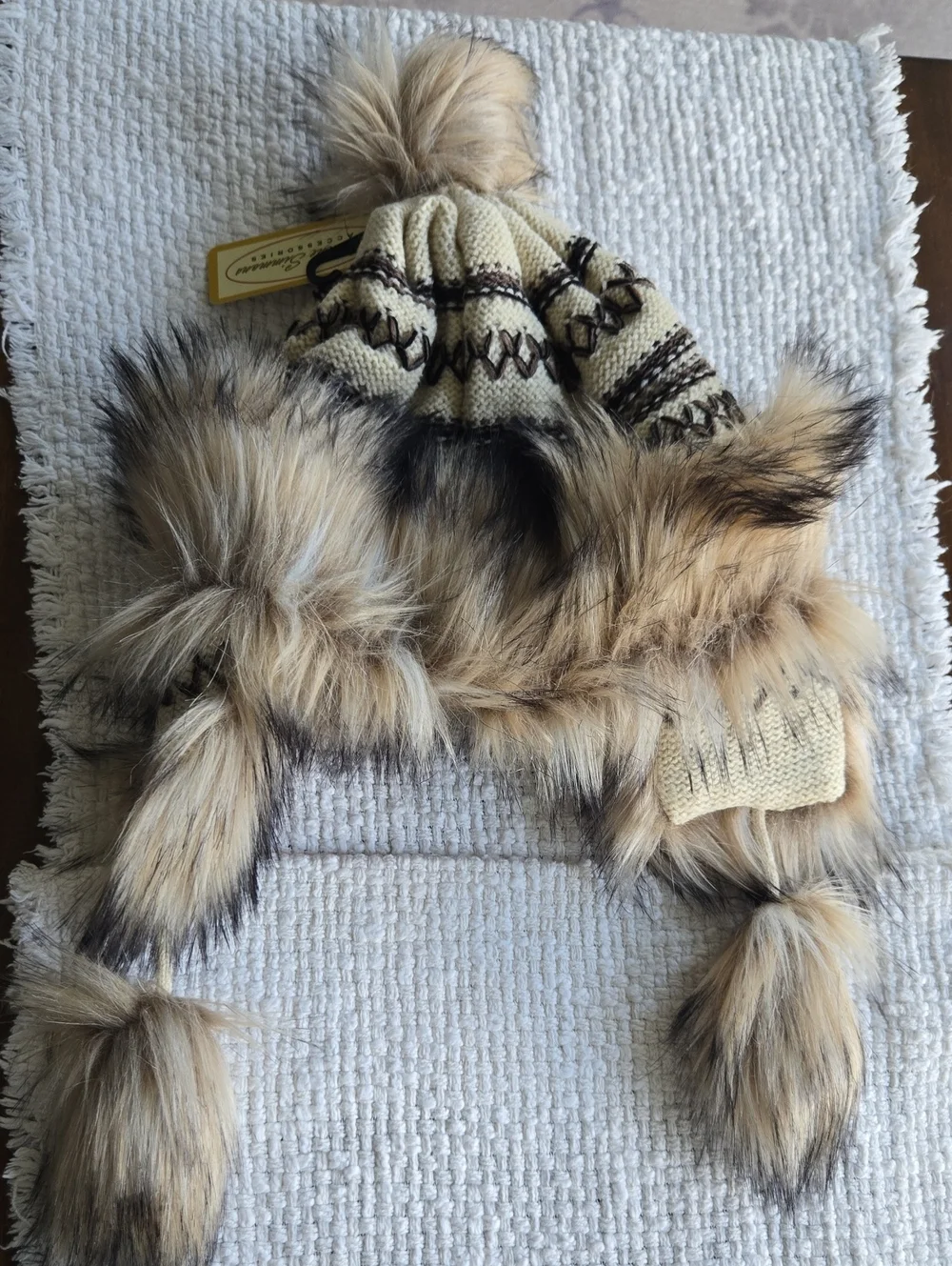 Cross stitch knit trapper beanie features a fleece lining, faux fur trim